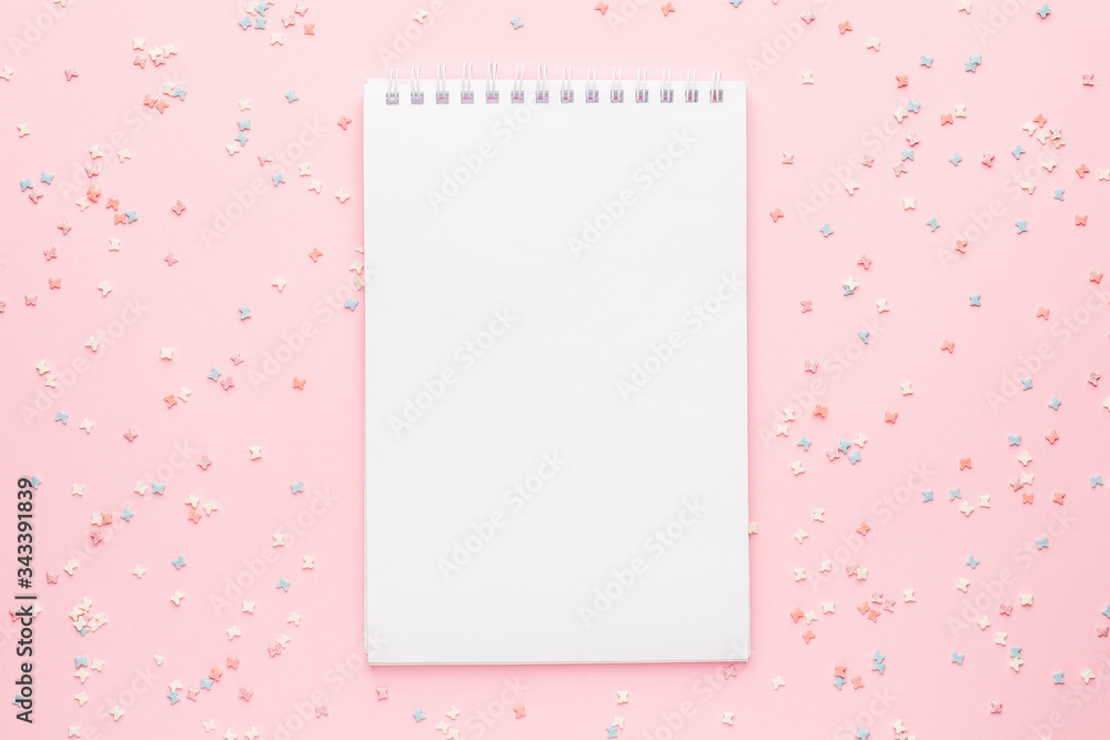 Notebook and sweet pastry topping on pink background