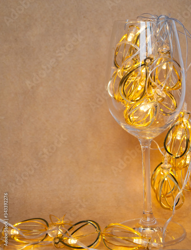 christmas wineglass with decoration garland lights on yellow background copy space