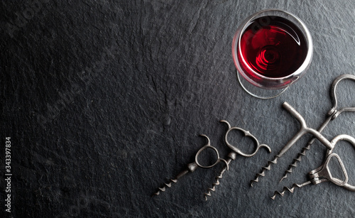 .Glass of red wine and corkscrews on a dark background..Glass of red wine and corkscrews on a dark background.