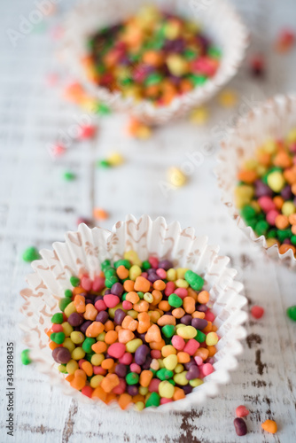 multicolored small candies in paper cupcakes on wooden background. Festive and birthday concept