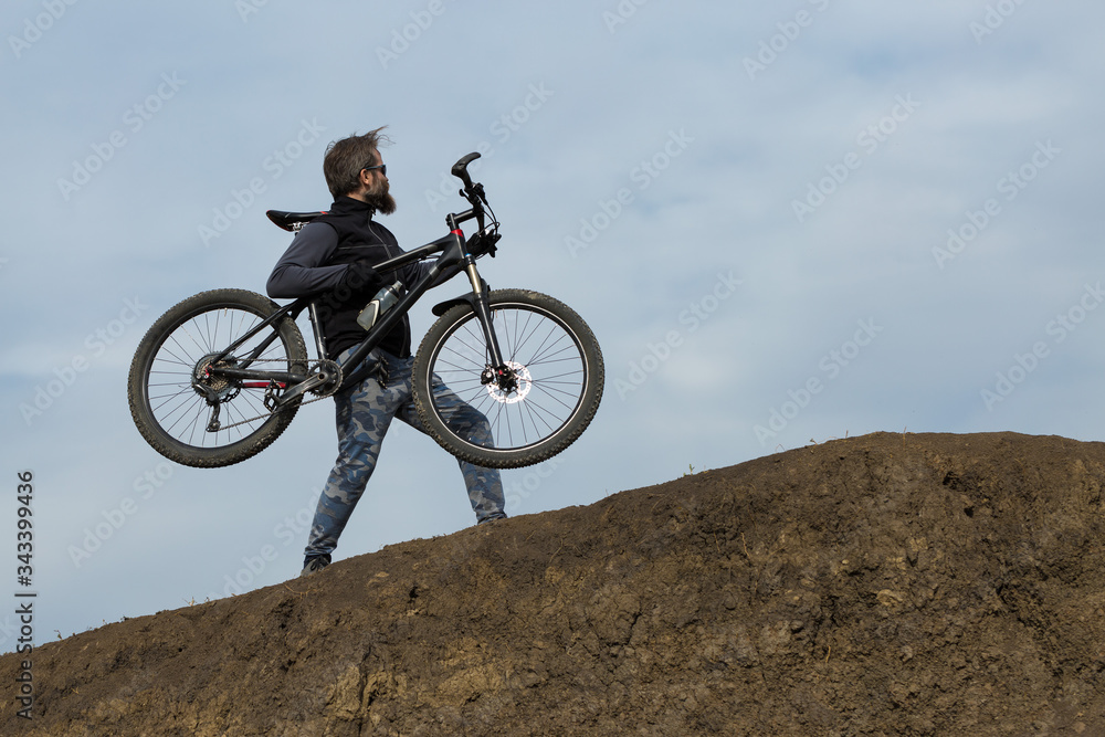 Sports brutal bearded guy on a modern mountain bike. Beautiful view from the mountain. Panoramic view for banner. Sports brutal bearded guy on a modern mountain bike. Beautiful view from the mountain. Panoramic view for banner.