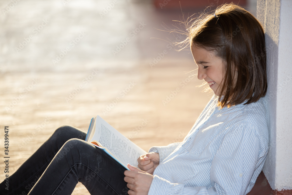 Laughing girl reading a book sitting on the rooftop Laughing girl reading a book sitting on the rooftop