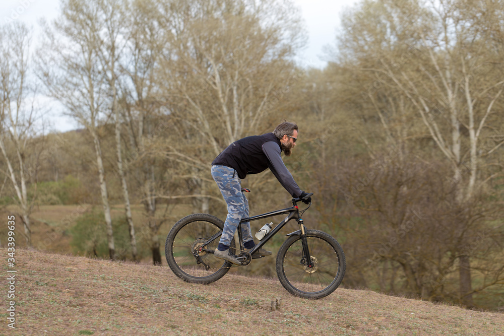 Sports brutal bearded guy on a modern mountain bike. Cyclist on the green hills in the spring. Sports brutal bearded guy on a modern mountain bike. Cyclist on the green hills in the spring.