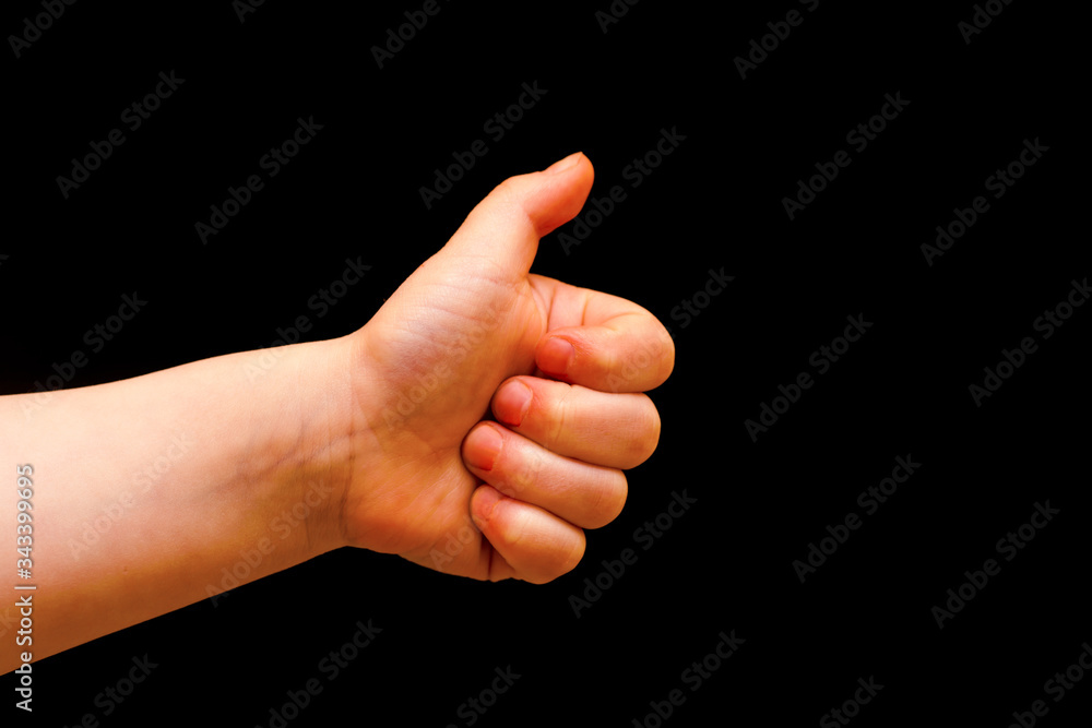 Like gesture on a black background. Child hand with like gesture, approval, thumbs up Like gesture on a black background. Child hand with like gesture, approval, thumbs up