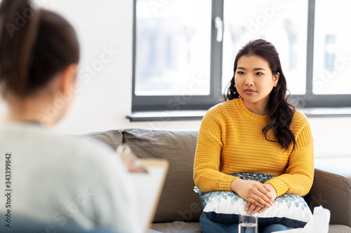 psychology and mental therapy concept - young asian woman patient and psychologist at psychotherapy session