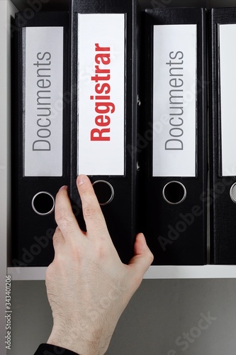 Registrar– finance/economics. File Folder is taken from office shelf. Male hand. Business, statistics