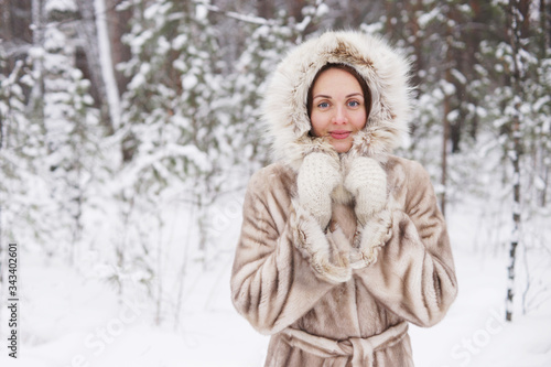 beautiful slim girl in light fur coat in winter park enjoy winter
