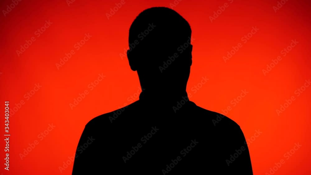 Silhouette of adult male on a red background waving with his head and rejecting what he is hearing. Silhouette of adult male on a red background waving with his head and rejecting what he is hearing.