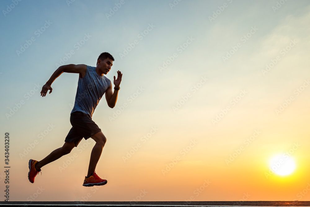 The silhouette of young men running and exercising at sunset with the sun in the background, colorful sunset sky