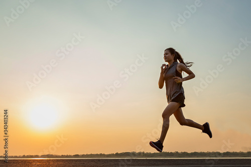 The silhouette of young women running and exercising at sunset with the sun in the background, colorful sunset sky.