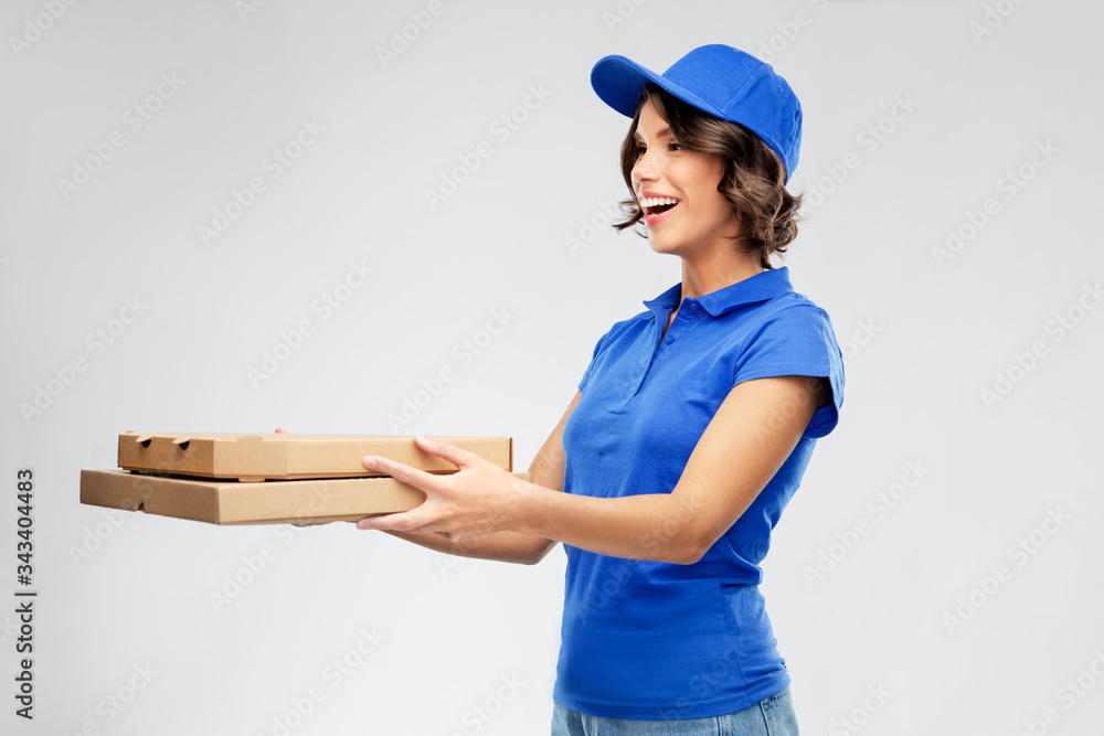 food, service and job concept - happy smiling delivery girl in blue uniform with takeaway pizza boxes over grey background food, service and job concept - happy smiling delivery girl in blue uniform with takeaway pizza boxes over grey background
