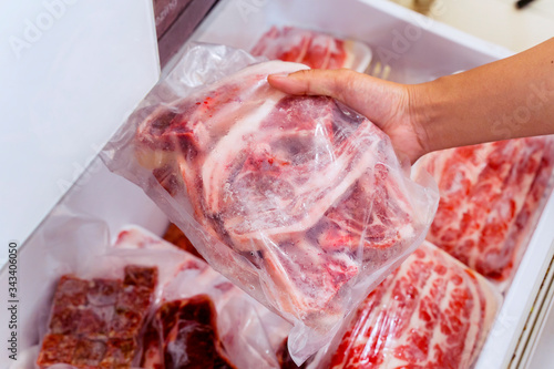 Hand choosing fresh raw ribs meat in freezer