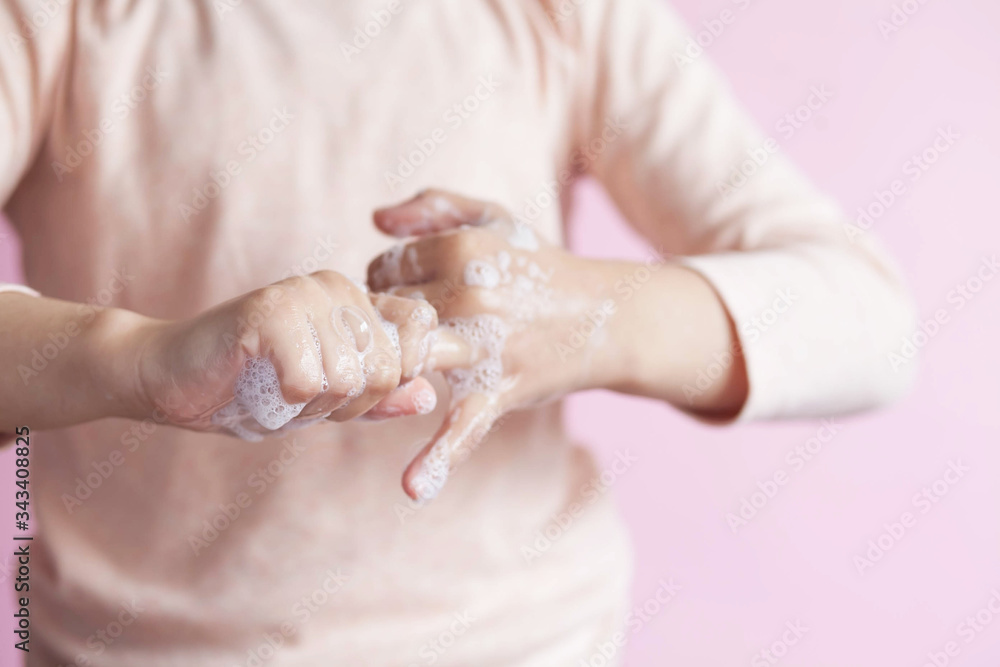 Child girl washes hands with soap on a pink background. Hand disinfection. Epidemic Covid-19. Child girl washes hands with soap on a pink background. Hand disinfection. Epidemic Covid-19.