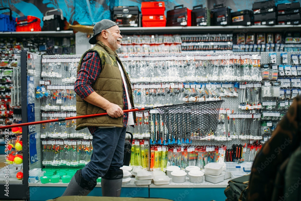 Fisherman with net and toolbox in fishing shop