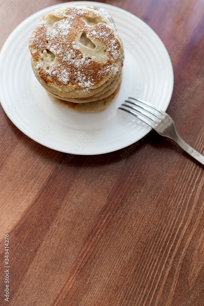 pancakes with berries and powdered sugar in a white plate are on the table pancakes with berries and powdered sugar in a white plate are on the table