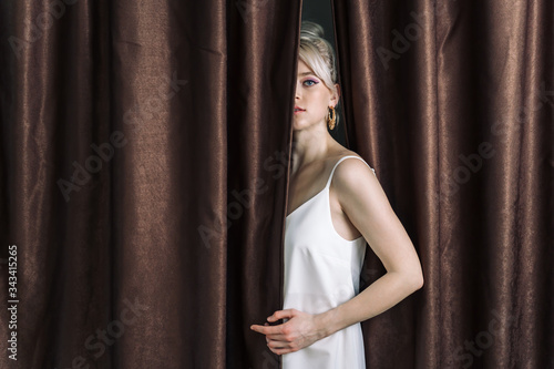 Sexy young blonde looking out from behind the curtains-2. © Alex Li