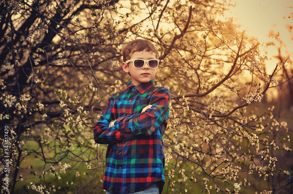 Portrait of a fashionable boy in sunglasses . A child in everyday clothes . Children in the spring Park