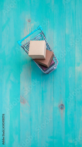 Shopping cart with boxes on wooden background © bohemama