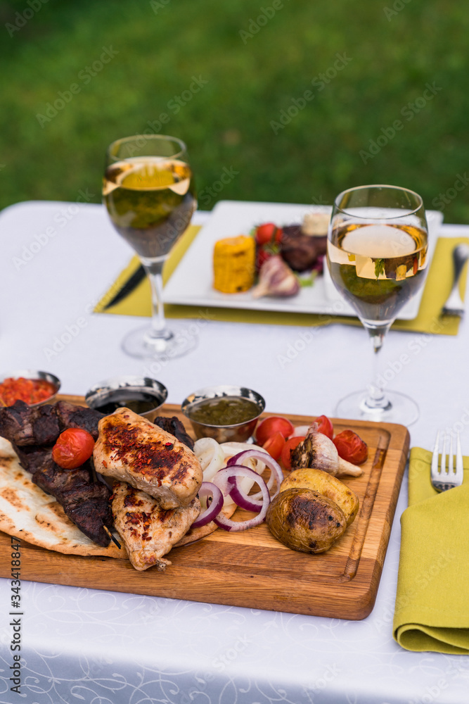 Served table for two with grilled meat and glasses of white whine