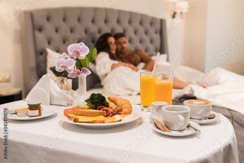 Tray with breakfast, room service, young couple have honeymoon in hotel