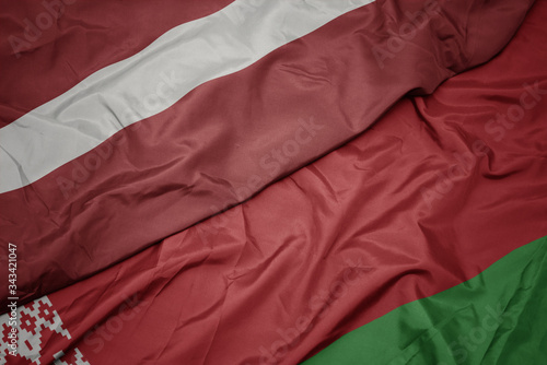 waving colorful flag of belarus and national flag of latvia.