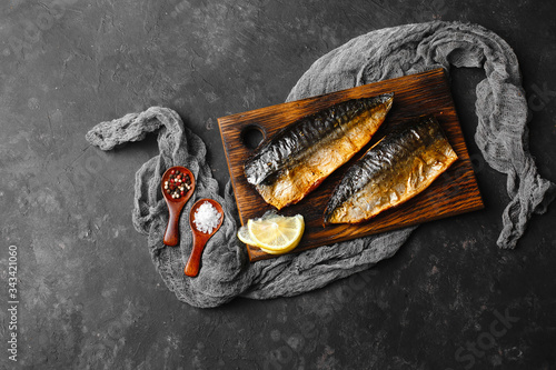 Delicious baked mackerel fillet with paprika, garlic and lemon, on a dark wooden Board with spices in the background. Top view, side view, close-up. Space for text.