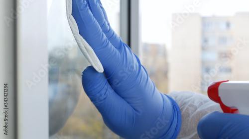 Close Up Man Hands with Protection Gloves Cleaning a Window Using Sprayed Liquid Disinfecting Against Viruses Contamination