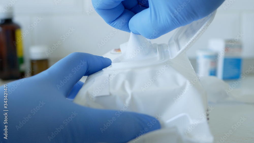 Fototapeta premium Social Distancing Lifestyle, Hands Protected with Gloves Taking Wet Wipes from a Package Used for Cleanliness