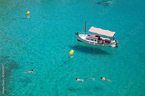 Fototapeta Bathers refresh themselves in the fresh and transparent waters of a bay on the island of Menorca in Spain