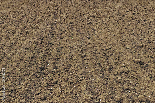 A close up of freshly tilled soil with till marks and textures in the dirt makes. Preparation for planting in the ground. Spring preparations for the garden season. Abstract background
