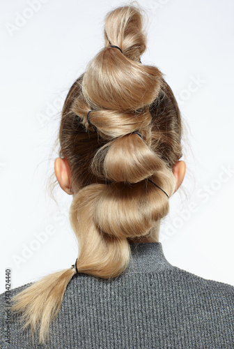 back view portrait of blonde female with creative braid hairdo.