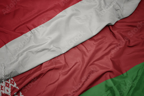 waving colorful flag of belarus and national flag of indonesia.