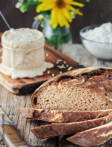Freshly baked homemade bread cut into pieces, closeup. The concept of healthy diet made from natural products, traditional craft bread based on natural sourdough. Sourdough and flour in the background