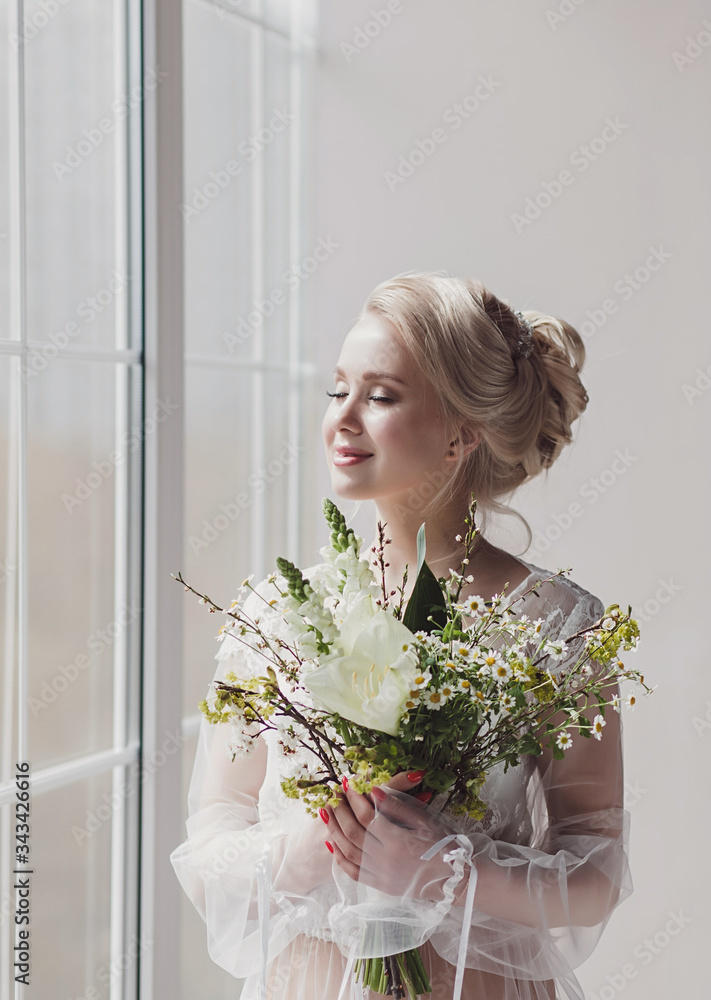 Romantic bride with wedding bouquet near window waiting groom