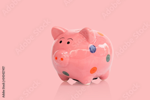 Pink ceramic piggy bank on pink background, saving money concept