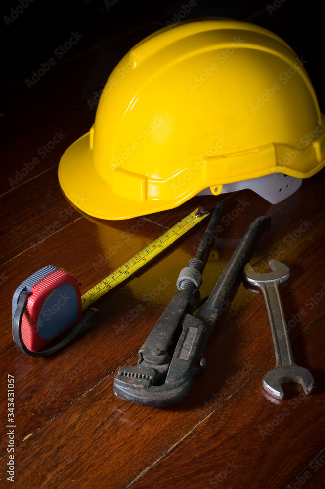 Fototapeta premium Metal wrench with tape measure and engineer helmet on table.