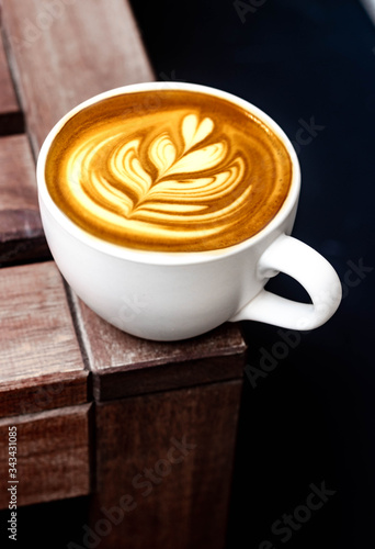 White cup of latte art barista cappuccino on a wooden table