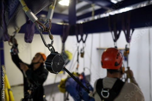 Fototapeta Naklejka Na Ścianę i Meble -  Safety work practices abseiler maintenance working at heights using an inertia reel shock absorber lanyard as fall arrest and connecting into back of body harness hook prior to used 