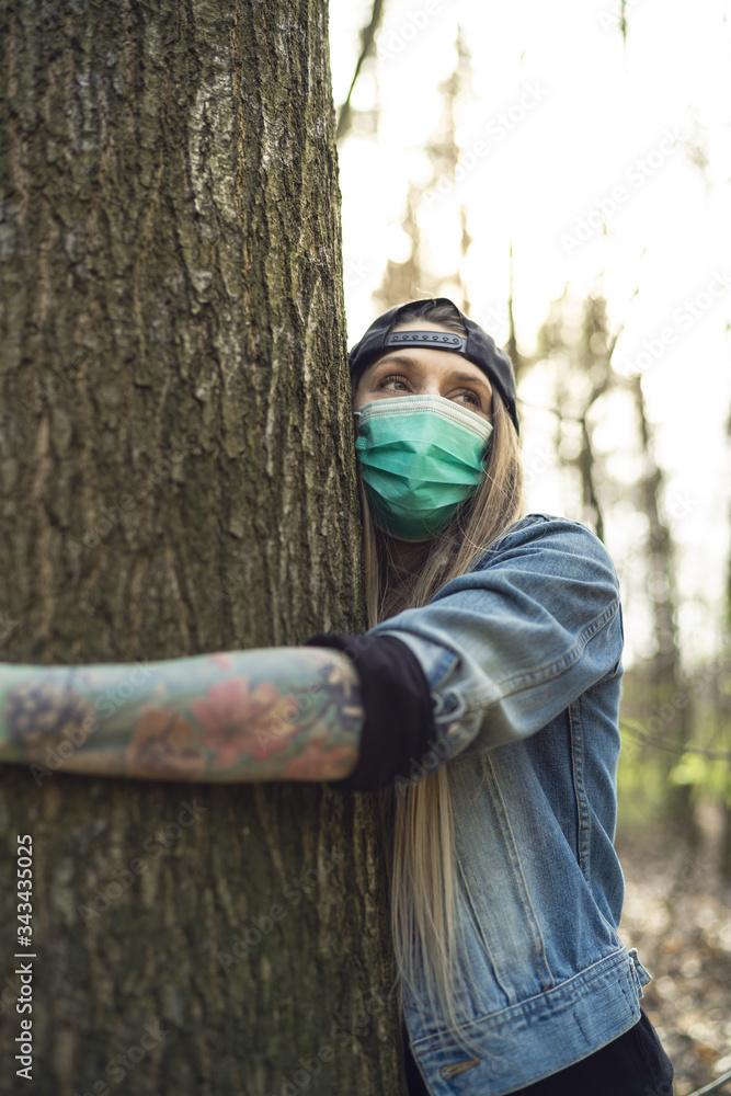 Casual Woman Hugging Tree in Park Wearing Face Protection Mask Against Coronavirus Casual Woman Hugging Tree in Park Wearing Face Protection Mask Against Coronavirus