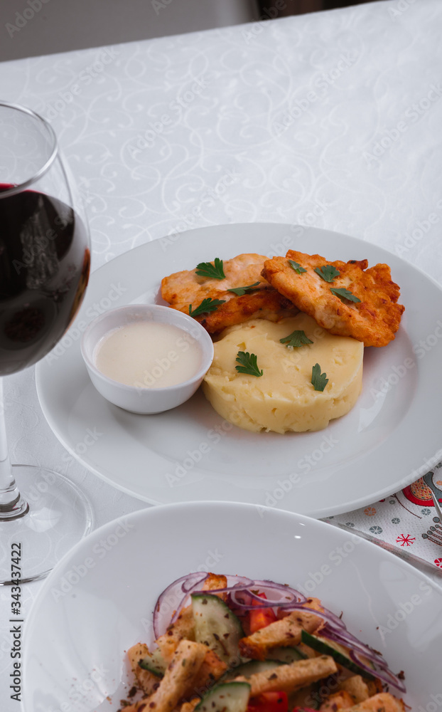 
dinner menu, feast and chicken cutlet with salad and red wine in combination with a tablecloth, tableware on the table