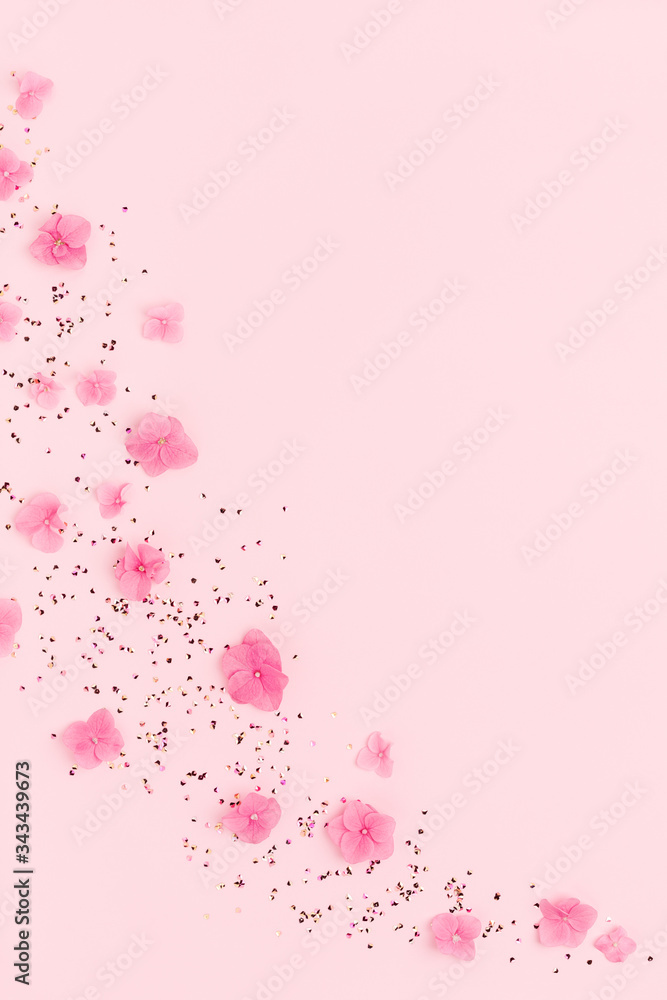 Frame of flowers and gold confetti spread on pink background. Spring Holidays, Birthday, Mothers Day, wedding. Copy space.
