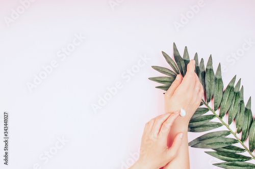 Woman moisturizing her hand with cosmetic cream, concept for feminine blog, social media, beauty concept photo