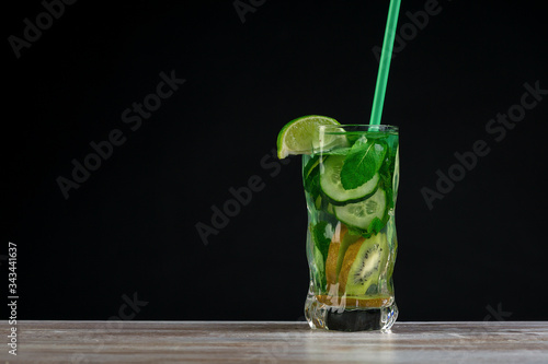 Citrus fruit and herbs in glass on wooden board, dark background