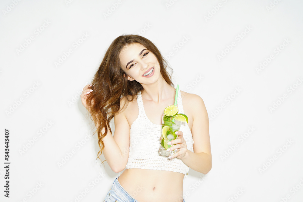 Healthy lifestyle brunette woman drinking with lime and mint cocktail with drinking straw in glass isolated on a white background Healthy lifestyle brunette woman drinking with lime and mint cocktail with drinking straw in glass isolated on a white background