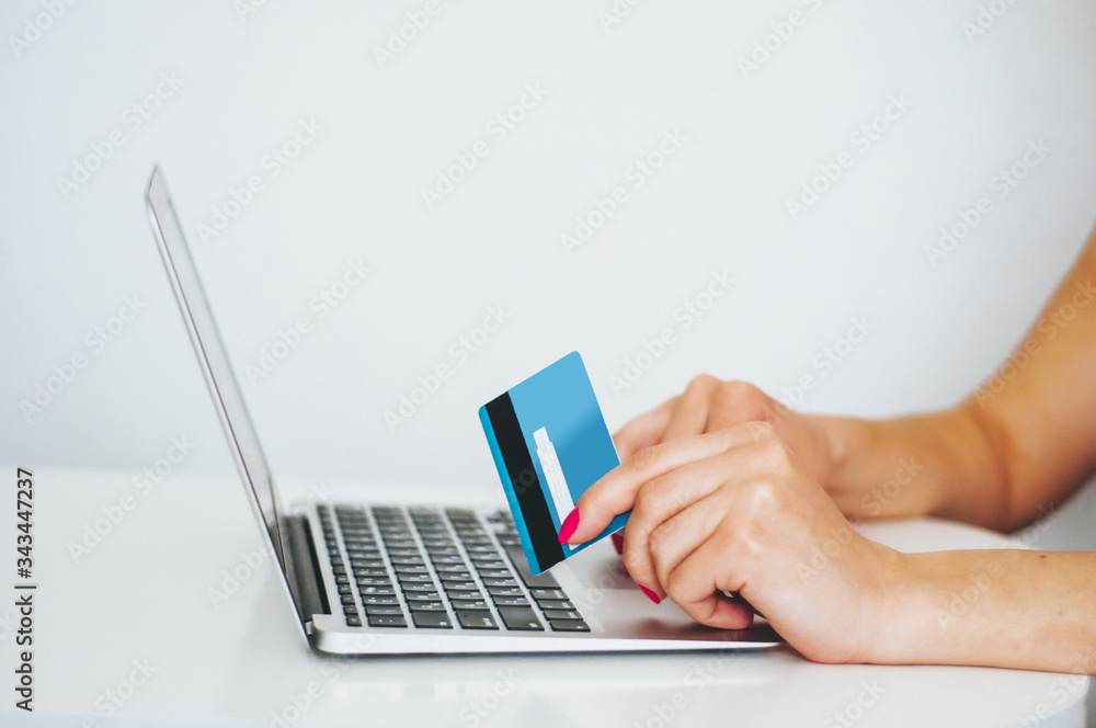 Hand holding credit card and using laptop. Businesswoman or entrepreneur working from home. Online shopping, e-commerce, internet banking, spending money, work from home concept Hand holding credit card and using laptop. Businesswoman or entrepreneur working from home. Online shopping, e-commerce, internet banking, spending money, work from home concept