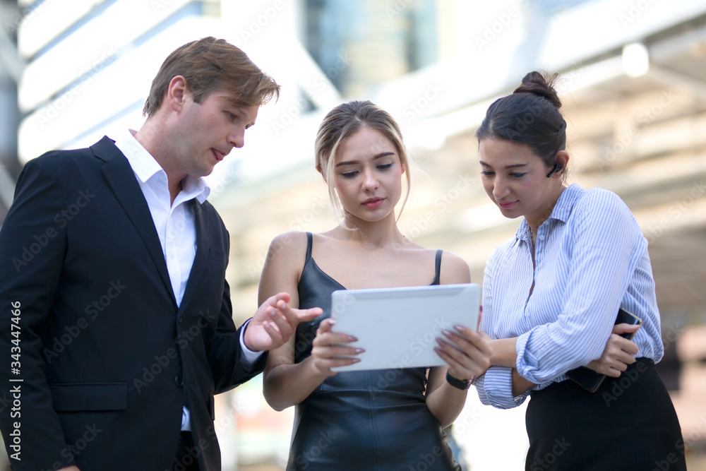 business team working together while looking on tablet business team working together while looking on tablet