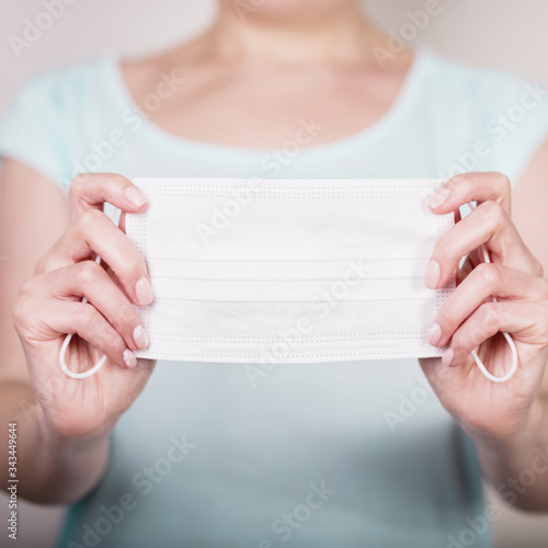 Female hands holding white medical mask. Concept of medicine, illness, protection, coronavirus. Copy space