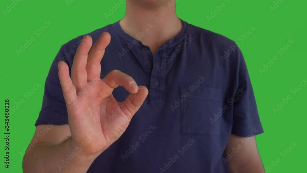 Male in blue T shirt lifts right hand to show Ok hand sign. Green screen Male in blue T shirt lifts right hand to show Ok hand sign. Green screen