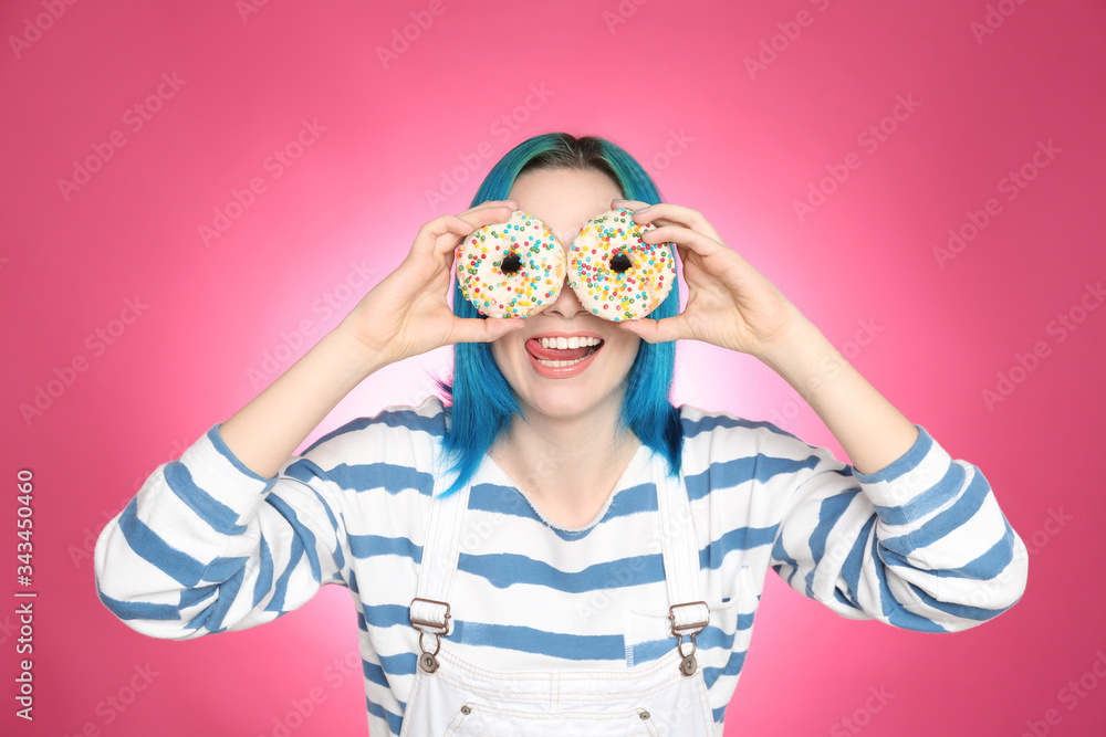 Young woman with bright dyed hair holding donuts on pink background Young woman with bright dyed hair holding donuts on pink background