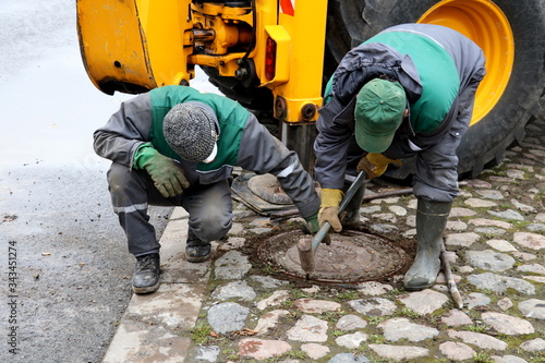 Workers try to open the manhole cover